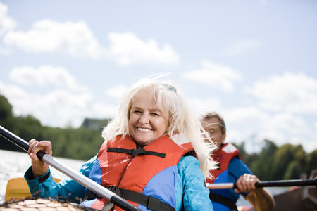 Happy senior active couple kayaking on lake enjoying time togetherの写真素材
