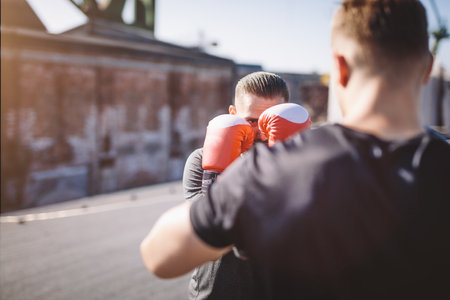 Two men do boxing training on the roof of the building in industrial area of the city, sparring and fightingの写真素材