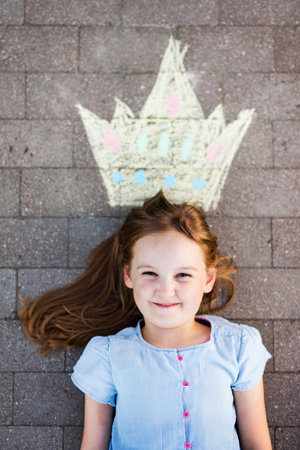 Young girl and crown painted on pavement in urban neighborhoodの写真素材