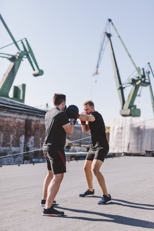 Two men do boxing training on the roof of the building in industrial area of the city, sparring and fightingの写真素材