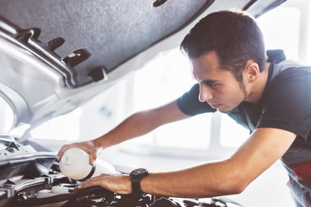 Car mechanic working in workshop checking engine. Service stationの写真素材