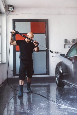 Service man washing car before detailing in workshop. Professional workの写真素材