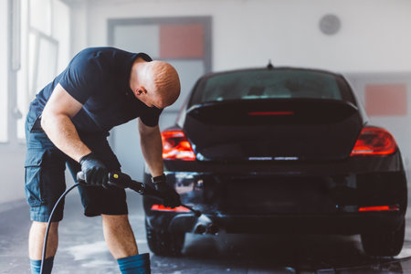 Service man washing car before detailing in workshop. Professional workの写真素材