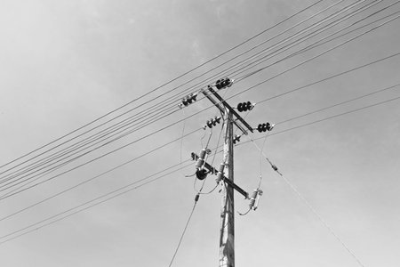 High-voltage power lines against the sky. Black and white photo.