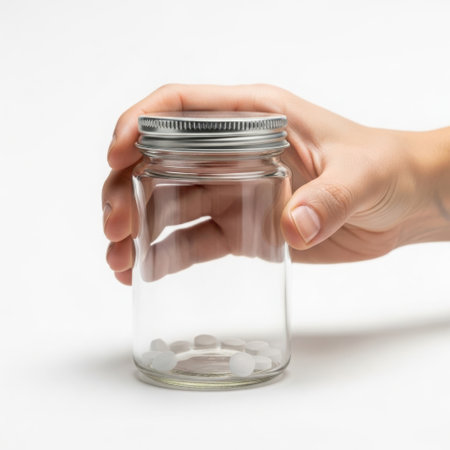 Hand holding empty glass jar with metal lidの素材