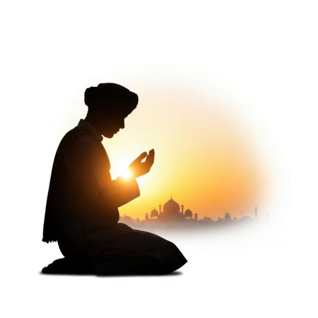 The image depicts a silhouette of an individual engaged in prayer, with hands clasped together in a gesture of devotion. The person is kneeling on the ground, and the scene is set against a backdrop of a city skyline at sunset. The sun is low on the horizon, casting a warm, golden glow that illuminates the scene. The cityscape includes several buildings, with a prominent dome-like structure visible among them.の素材