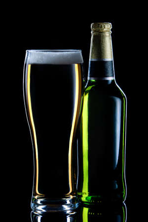 Closed bottle of beer  and full glass on dark backgroundの写真素材