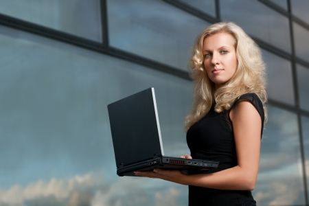 Attractive business lady is  holding a laptop and looking at the cameraの写真素材