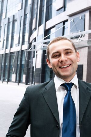 Portrait of smiling businessman in front of office buildingの写真素材