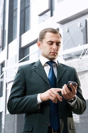 Young and successful businessman is reading a message on his smartphoneの写真素材