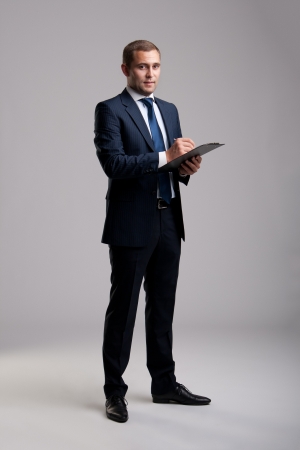 Young and successful businessman holding a clipboard and signing a documenの写真素材