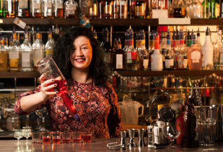 Bartender  pouring alcohol into shot glassesの写真素材