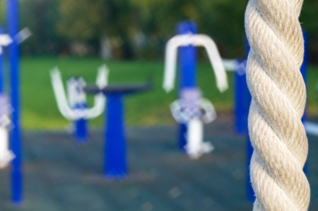 Playground outdoor fitness equipment in the blurred image, to the right a fragment of the rope is depicted sharply, soft focus.の写真素材