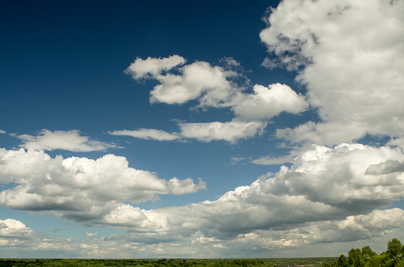 The sky filled with lots of cumulus clouds over a low horizon line.の写真素材