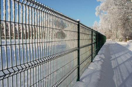 The metal fence in the winter Park is depicted in a sharp perspective, occupies half of the image field, close-up.の写真素材