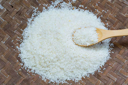 Rice is in wooden spoon on the rice as tray background.の写真素材