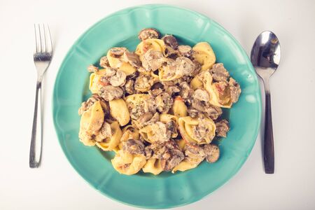 Tortellini pasta with mushrooms on a plate with tablewareの写真素材