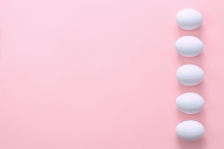 Easter eggs in a row on a pink background. Easter holiday creative greeting card. Flat lay. From above. Copy spaceの写真素材