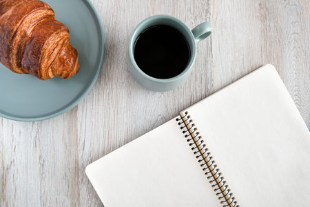 Breakfast. Morning coffee, croissant and notebook. Top view.の写真素材
