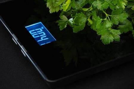 Green parsley is on an electronic weight on a black background.の写真素材