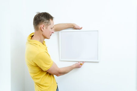 Man is deciding where the picture will hang.