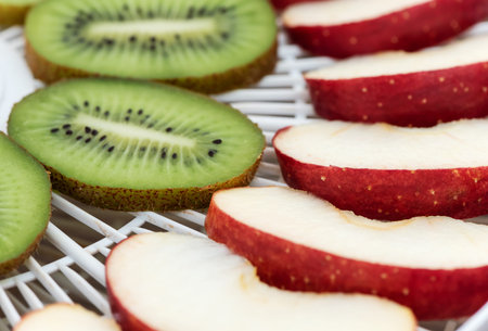 Dehydrator tray with slices of apples and kiwi. Macro.の写真素材