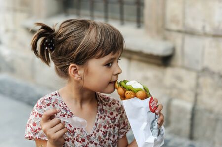 Girl is eating a ice cream with fruits and waffle bubbles outdoors.の写真素材