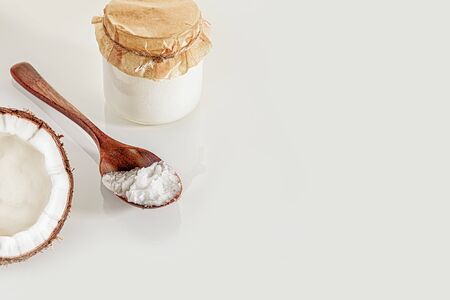 Composition with half of the coconut, wooden spoon and jars of coconut butter. The concept of healthy food.の写真素材
