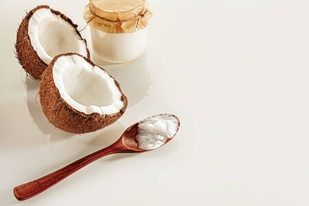 Composition with two halves of coconut, a wooden spoon and jars of coconut butter. The concept of healthy food.の写真素材