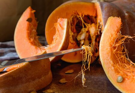 The fibers are on the tip of the knife on the background of the cut pumpkin.の写真素材