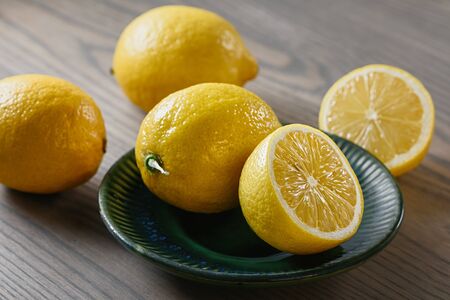 Whole lemons and halves on a green plate and on a wooden table top.の写真素材