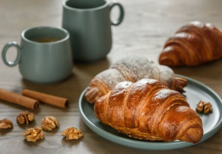 Breakfast. Croissants, walnuts, cinnamon and two cups of coffee on the wooden background.の写真素材
