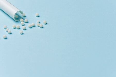 Homeopathy concept. Homeopathic balls are spilled from a bottle on a blue background.の写真素材