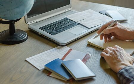 Man with laptop and notebook planning trip. Travel and vacation concept.の写真素材