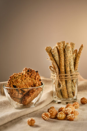 Still life with bread sticks, oatmeal cookies and breadballs. Grissini is in the glass. Cookies are...