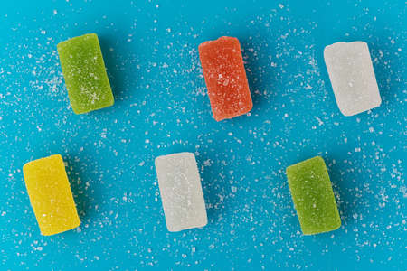 Multicolored jelly candies are sprinkled with sugar on a black background.の写真素材