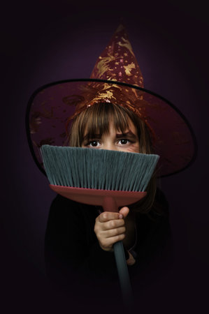 The witch girl is covering her face with a broom.