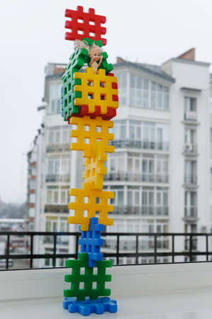 Construction toys. Tower with a doll on the background of a residential building.の写真素材