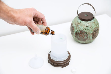 The man's hand is filling with water a capacity of aroma diffuser.