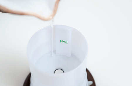 The man's hand is filling with water a capacity of aroma diffuser.