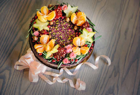 Cake decorated with fresh fruit, flowers and hazelnuts.の写真素材