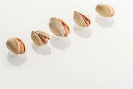 Pistachios. Unpeeled nuts on a white glass surface.の写真素材