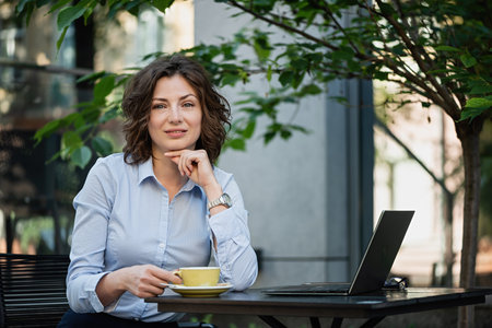 Beautiful business woman is sitting at a table in a outdoor restaurant.