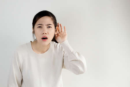 Asian beautiful deaf women with hearing problem use hand cup ear to listen news, information and communication.の写真素材