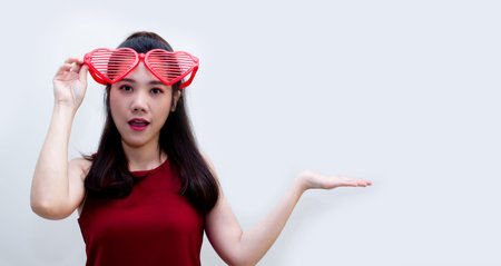 Asian beautiful woman with red theme on white background are wearing red big heart shape glasses...