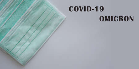 Green mask on flat lay and white background with text of COVID19 OMICRON to encourage people wear mask in order protect themselves from COVID-19.の写真素材