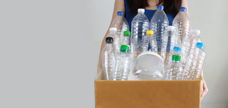 Woman are carry recycled plastic bottle which contain in carton box for sustainability and...