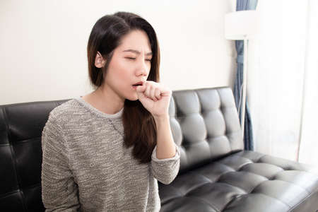 Asian beautiful woman sitting in living room are cough . A Healthcare concept.の写真素材