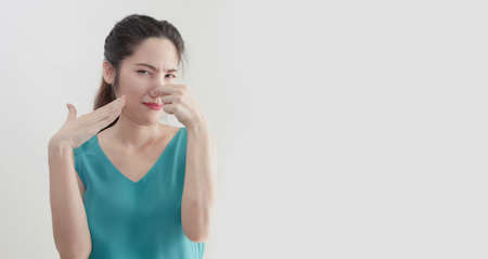 Asian beautiful women who covers and touching  nose, looks away, something stinks, very bad smell with unhappyの写真素材
