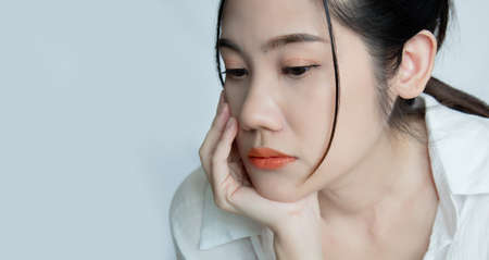 Asian beautiful woman touch her chin with hand  and feeling worried and sad. A Metal concept and Broken heart.の写真素材